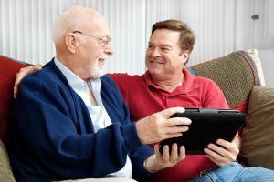 Senior man using tablet PC with his adult son.